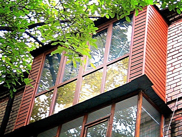 Аккуратный балкон, обшитый сайдингом под дерево.